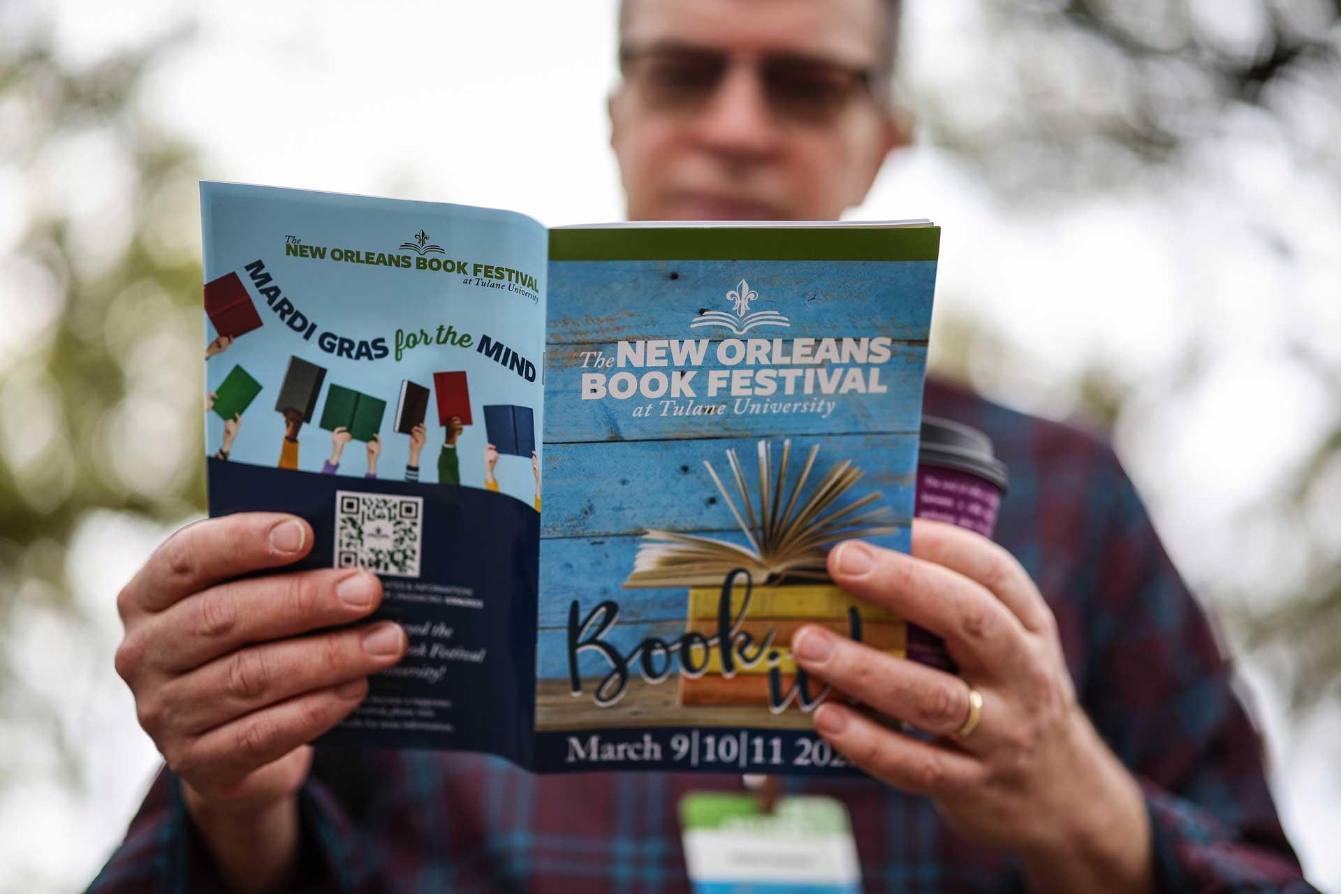 A man looks through a Book Festival program book.